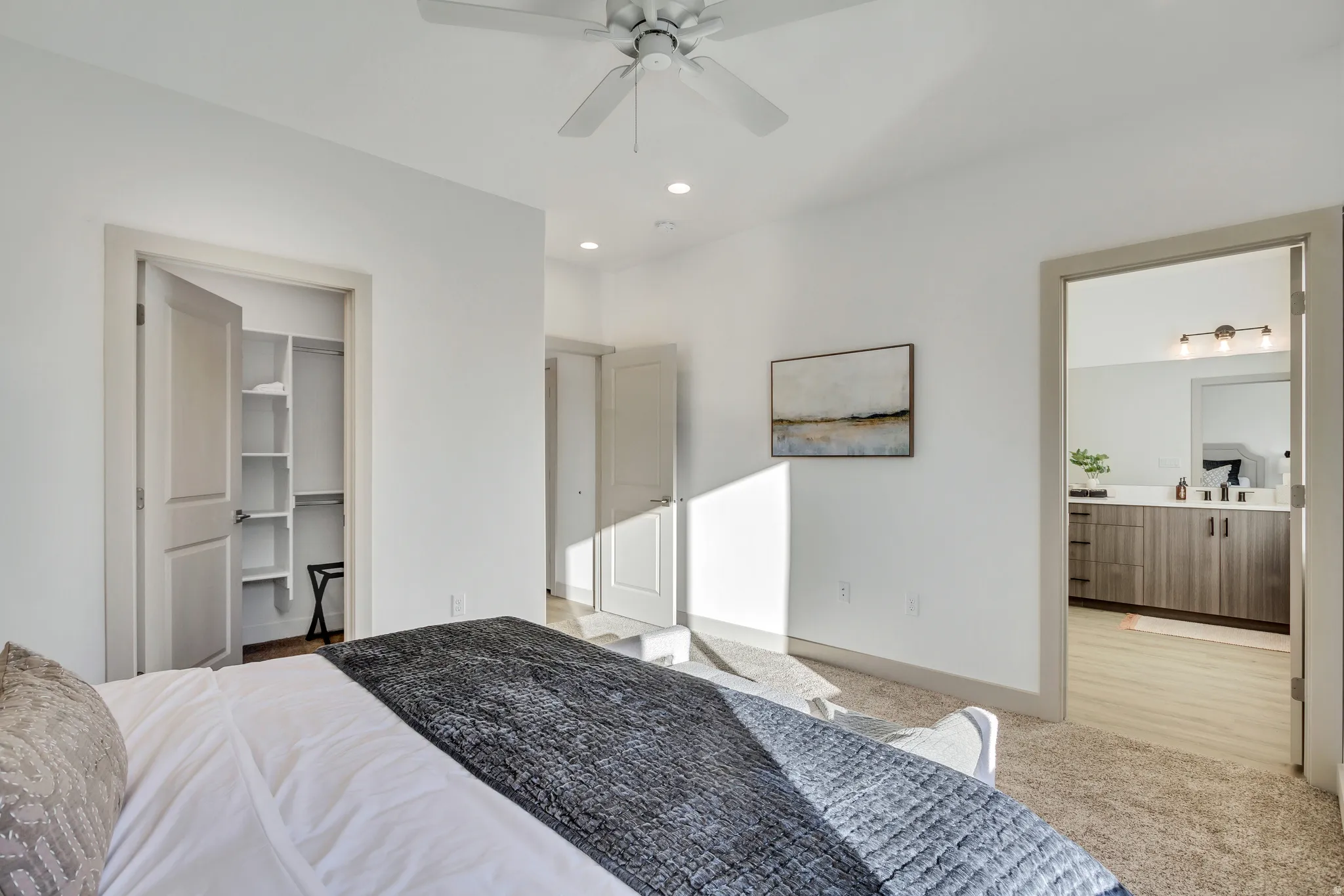 White ceiling fan, recessed lighting, carpeted flooring, built-in closet shelving, wood-finish bathroom vanity