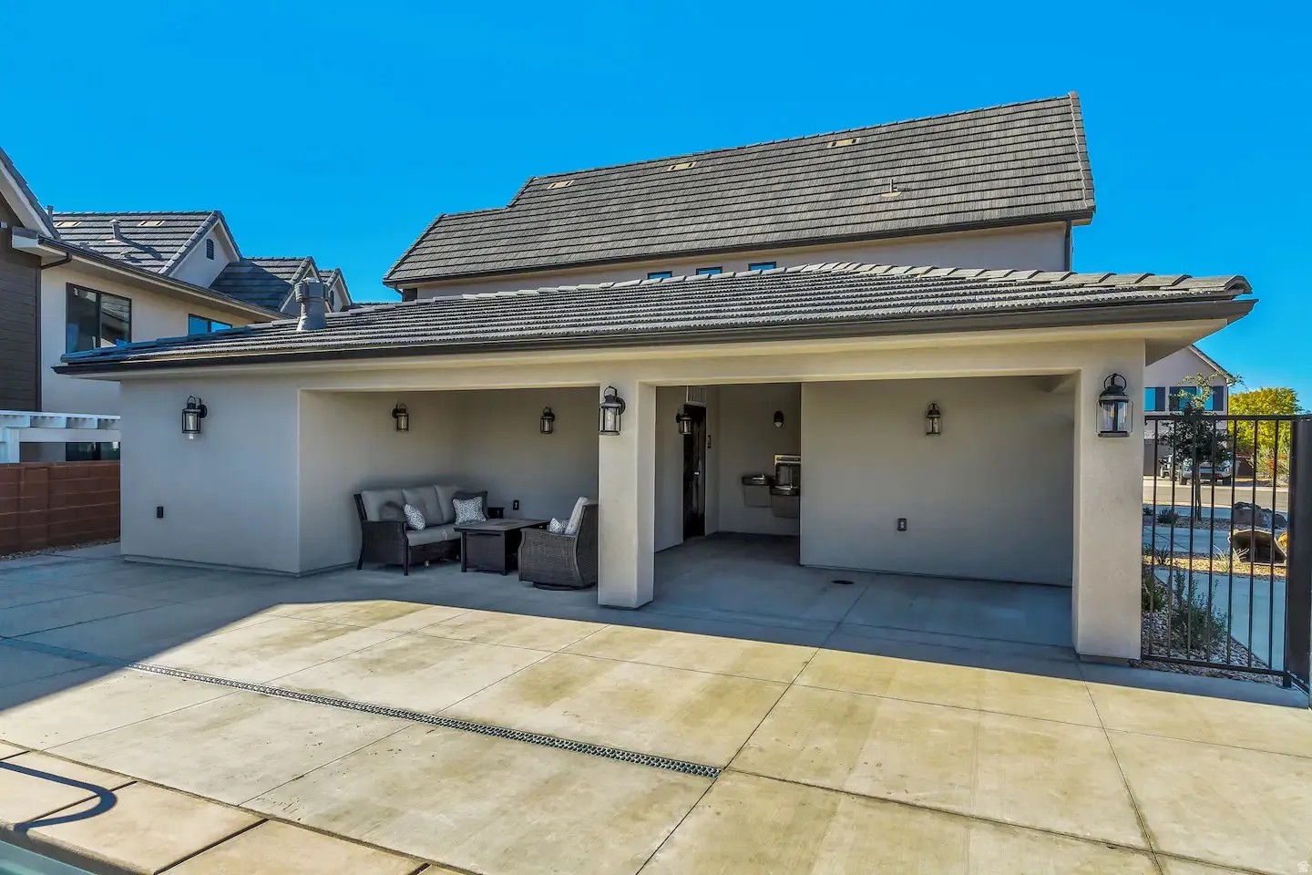 Covered outdoor living space featuring an outdoor kitchen, exterior wall-mounted lighting, and a tile roof
