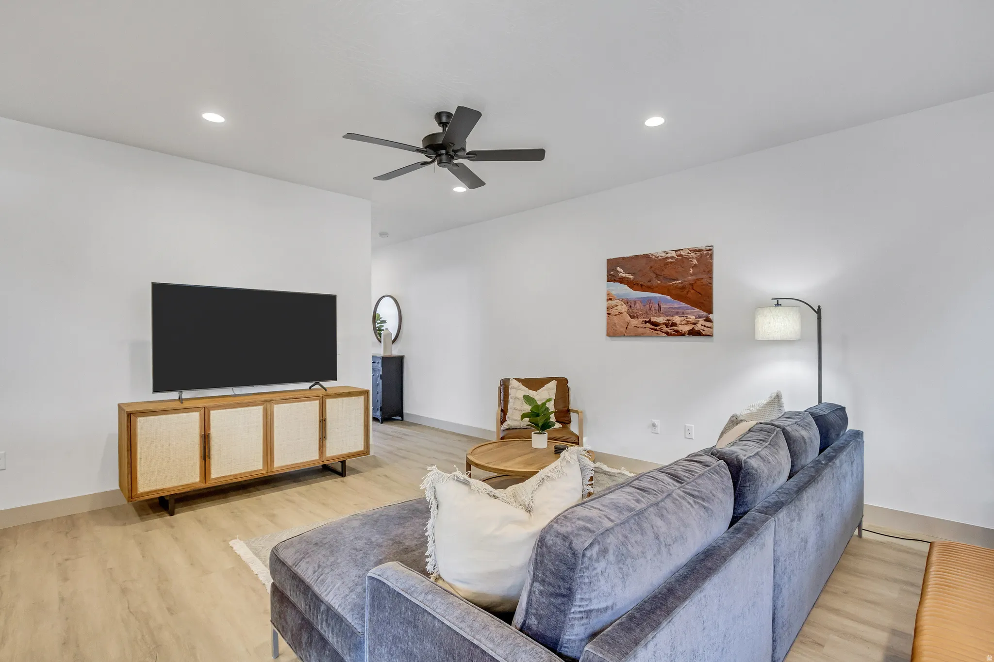 Recessed lighting, wood-finish flooring, and a ceiling fan enhance this living area