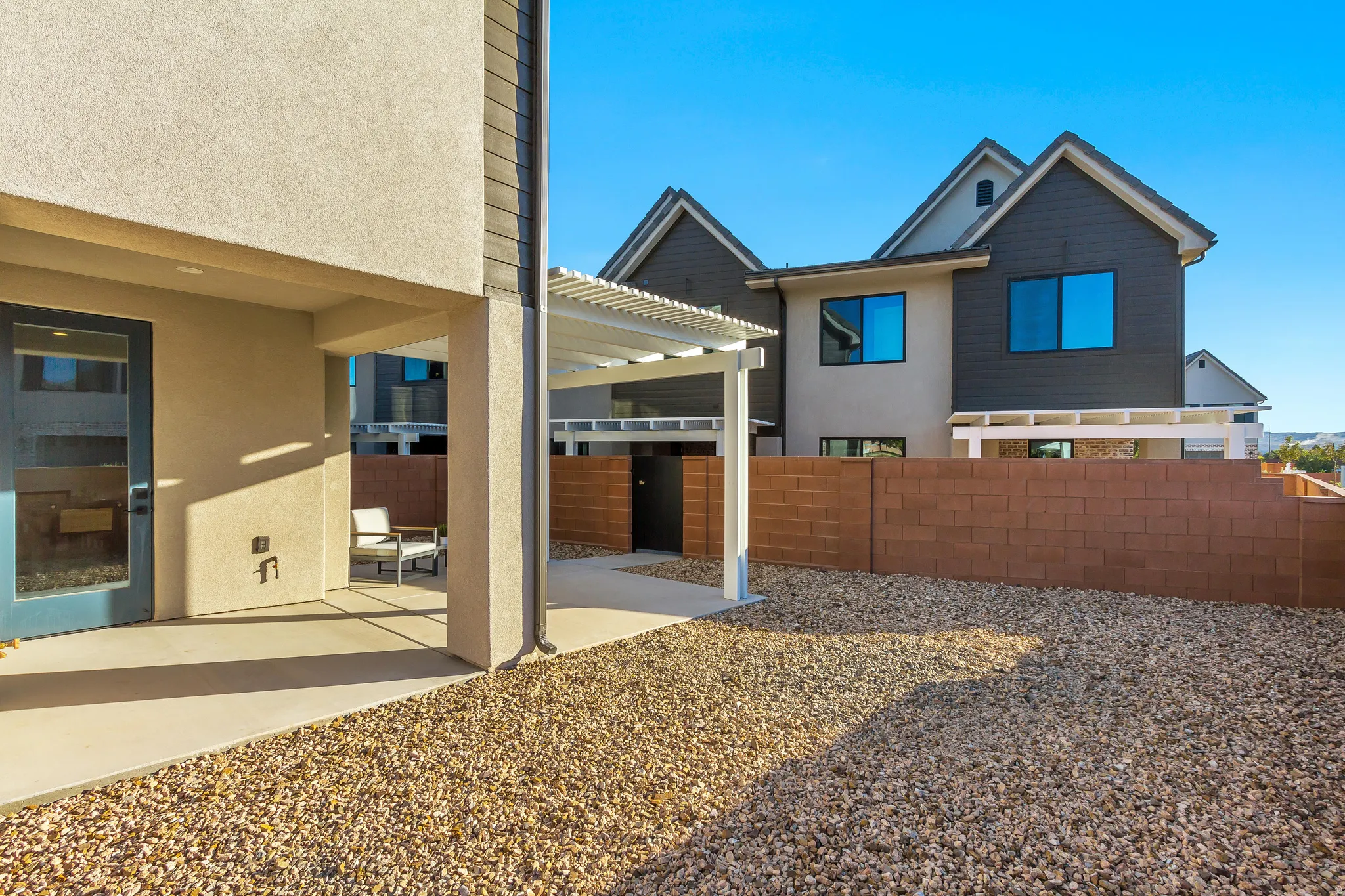 Rear exterior featuring a covered patio, gravel landscaping, and a privacy wall