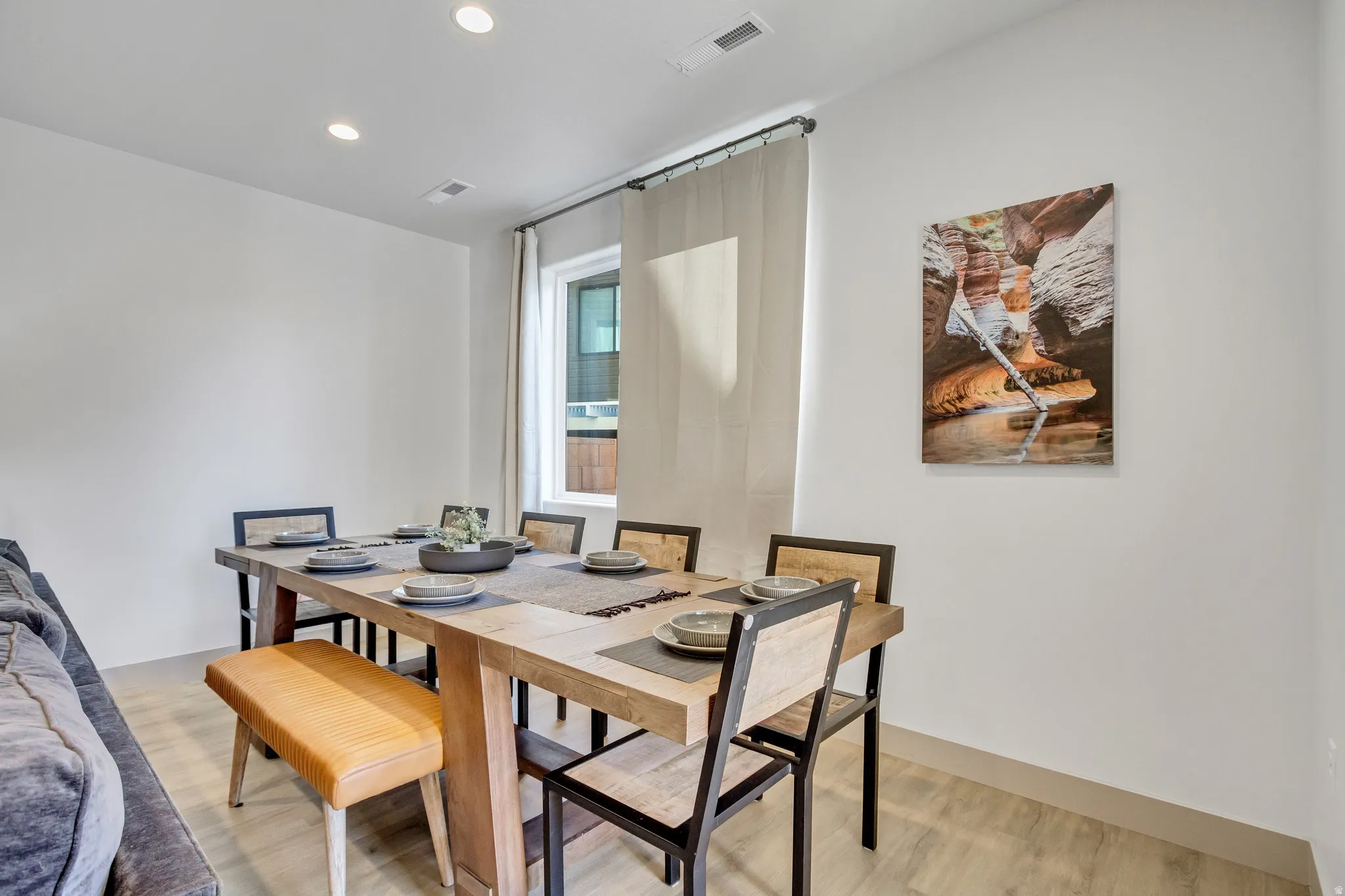 Modern home office featuring a wood-finish dining table with black metal frame, natural wood bench seating, and coordinating chairs