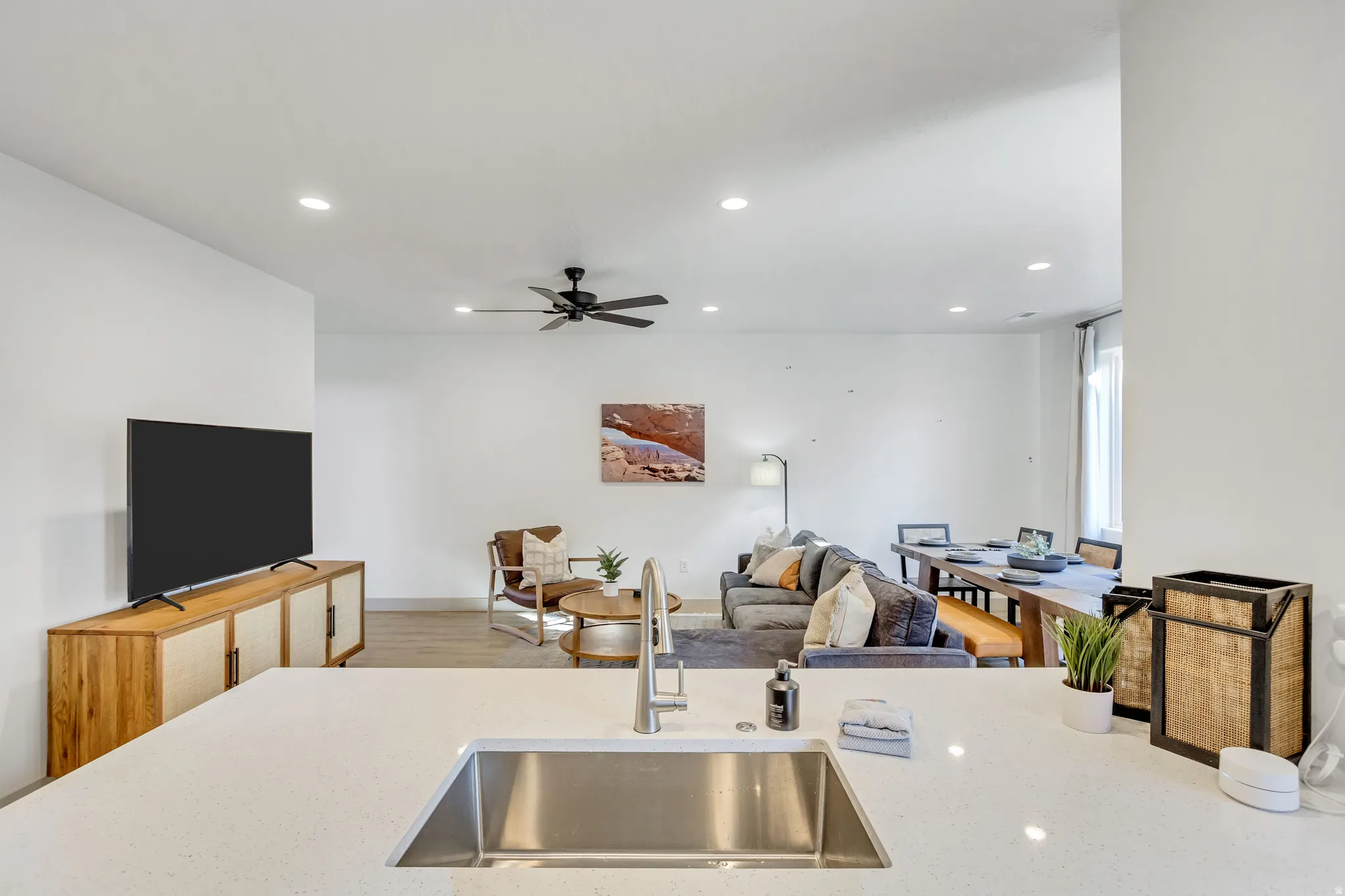 Kitchen island with an undermount stainless steel sink and stainless steel faucet, recessed lighting, wood-finish flooring, and a ceiling fan