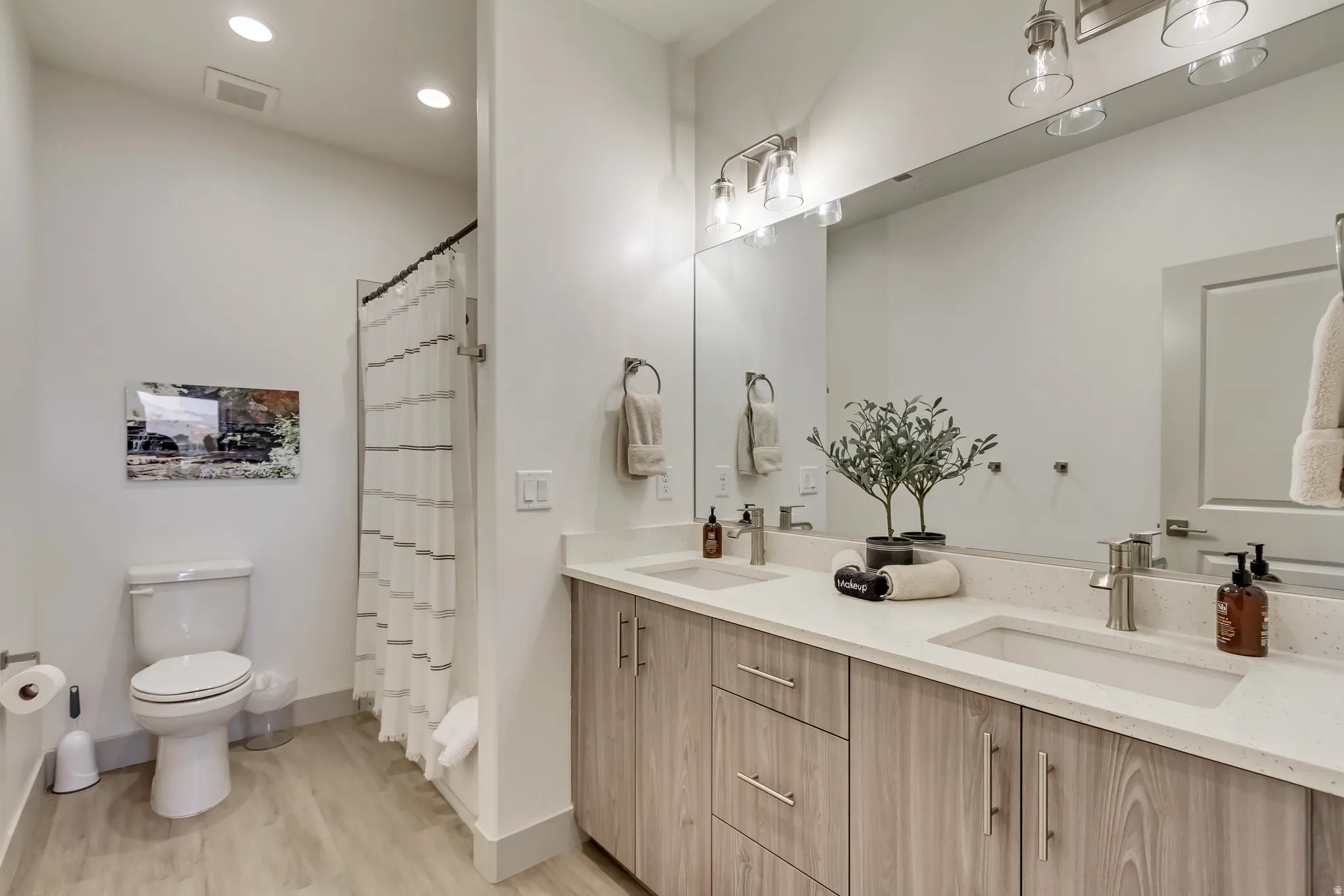 Double vanity with undermount sinks, wood-finish cabinetry, and light-toned countertops