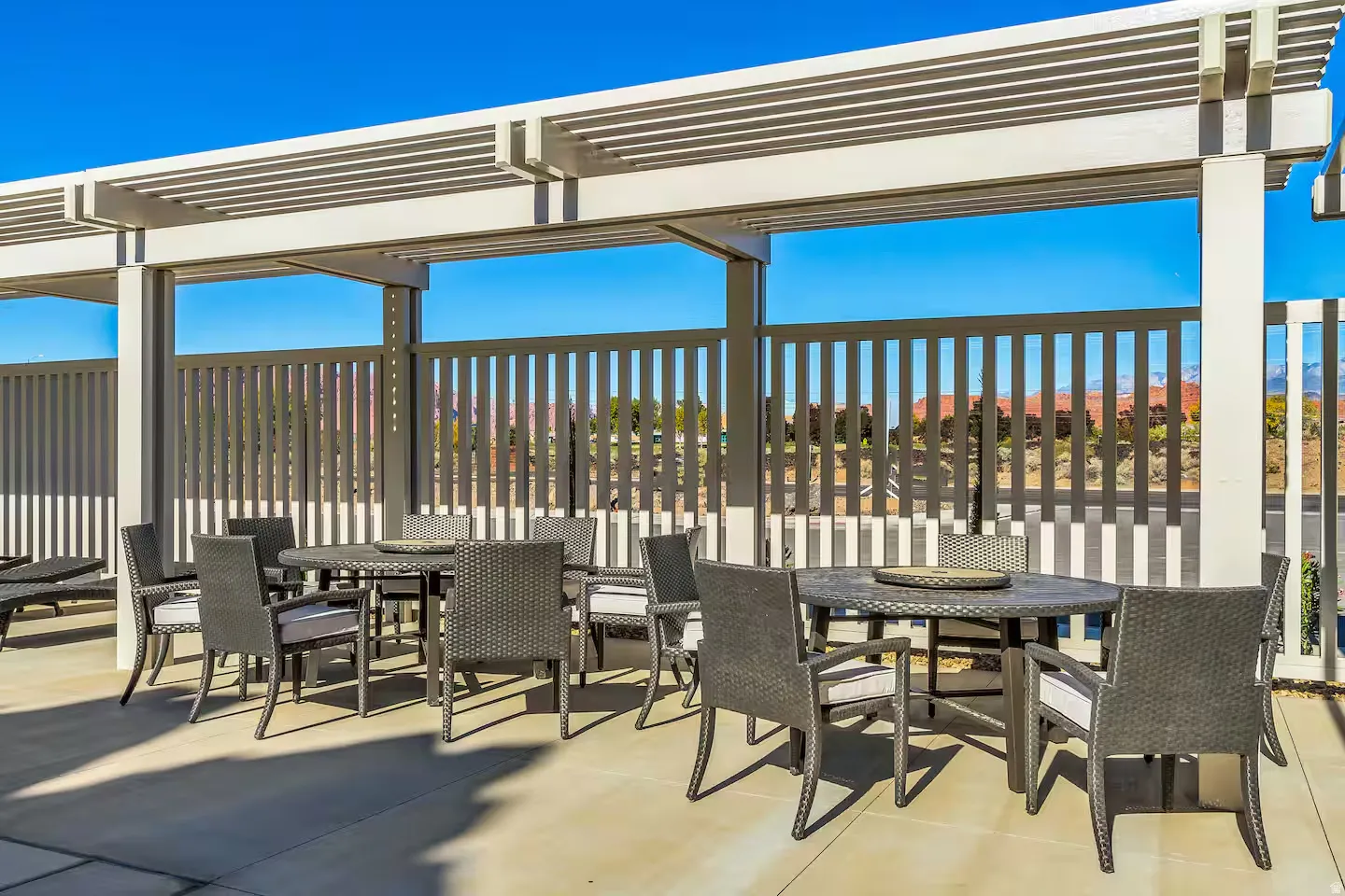 Expansive covered patio featuring a slatted pergola, concrete flooring, and privacy fencing