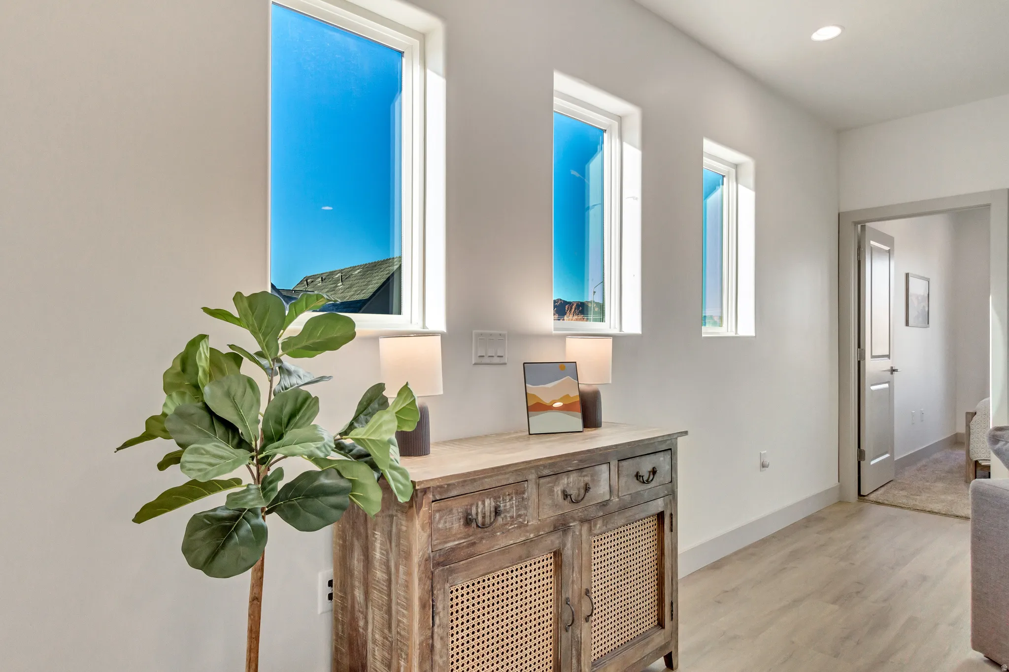 Recessed lighting, wood-finish flooring, white walls, and a light gray interior door