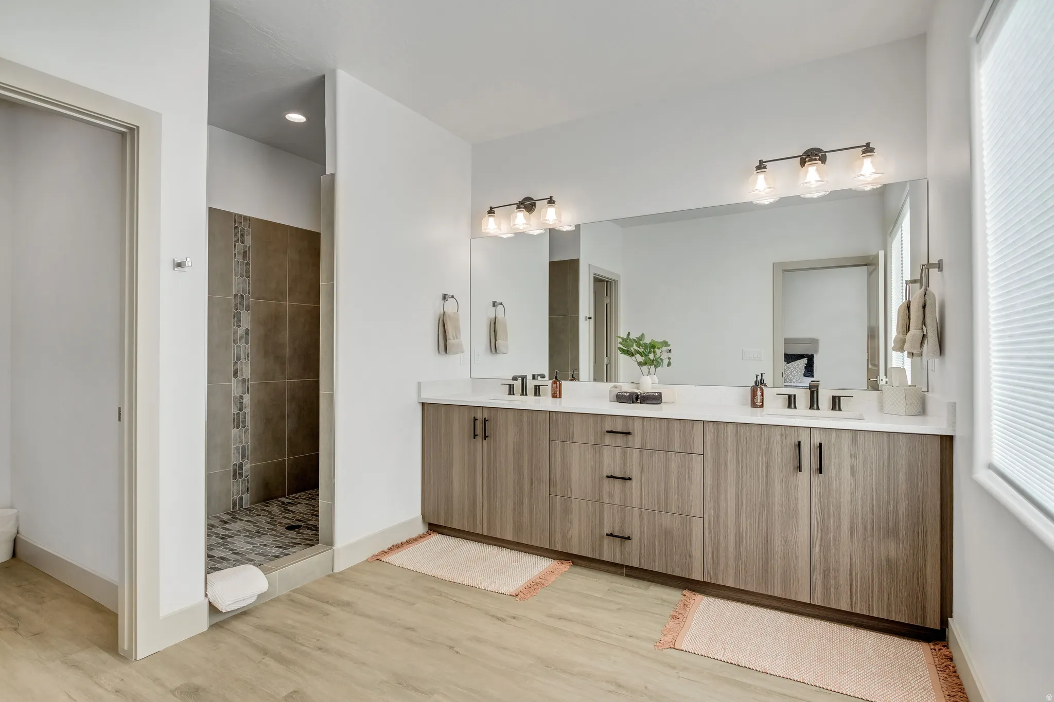 Dual vanity with wood-finish cabinetry, white countertops, and undermount sinks