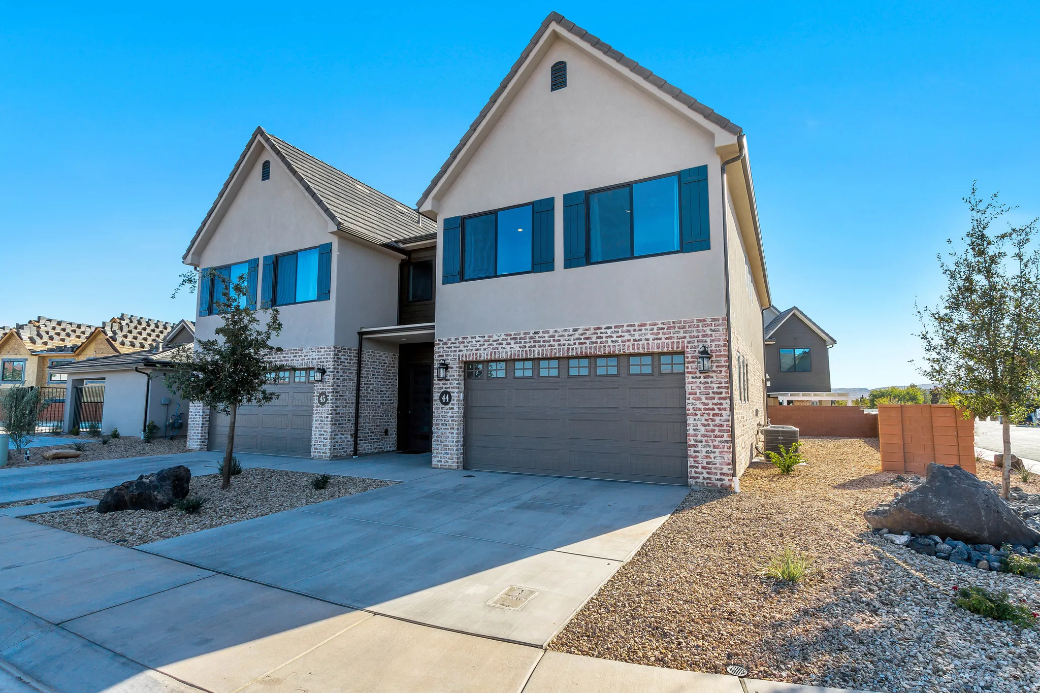Modern stucco and brick exterior featuring gabled roofs and dark window shutters