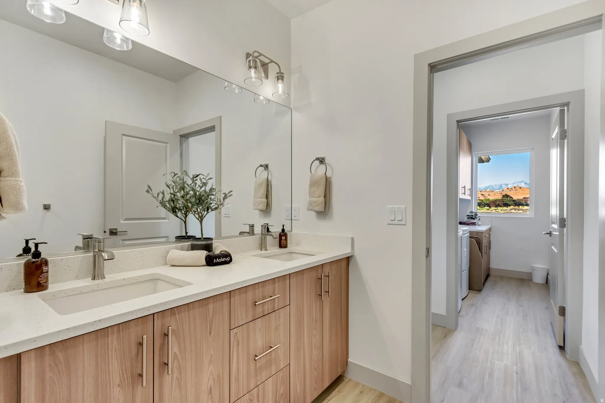 Double vanity with light wood-finish cabinetry, white countertop, and brushed nickel fixtures