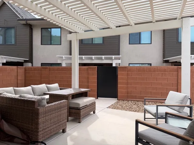 Paved patio with a white pergola, surrounded by a block wall and gravel landscaping