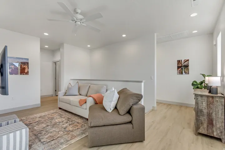 Recessed ceiling lighting, wood-finish flooring, ceiling fan, and white painted walls