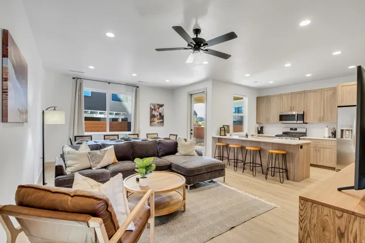 Open-concept living space featuring wood-finish flooring, recessed lighting, a modern ceiling fan, and a kitchen island with seating
