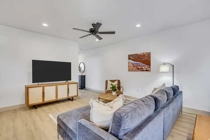 Recessed lighting, wood-finish flooring, and a ceiling fan enhance this living area
