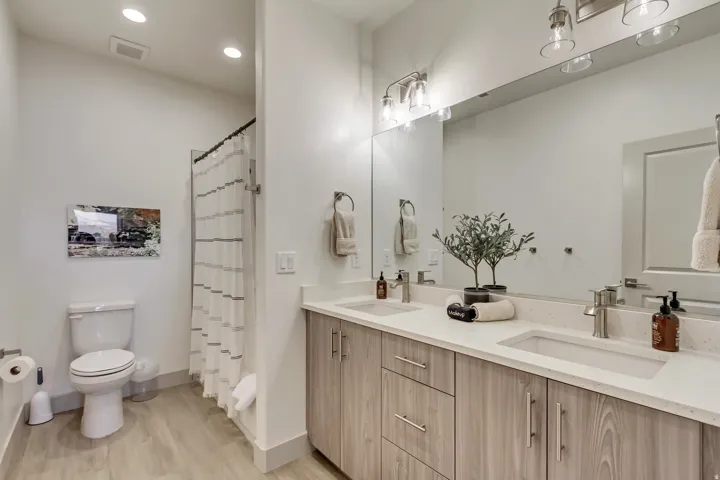 Double vanity with undermount sinks, wood-finish cabinetry, and light-toned countertops