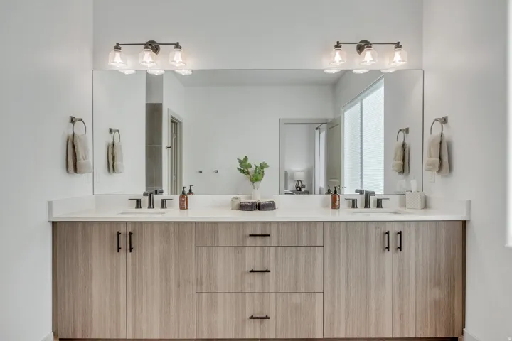 Dual-sink bathroom vanity featuring wood-finish cabinetry with black hardware, white quartz countertops, and matte black faucets