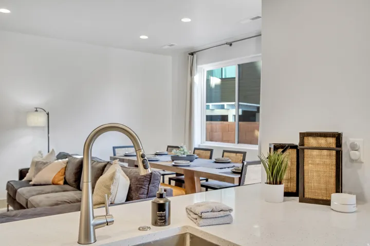 Stainless steel pull-down faucet with a single basin sink, white countertops, recessed lighting, and a large window with white trim