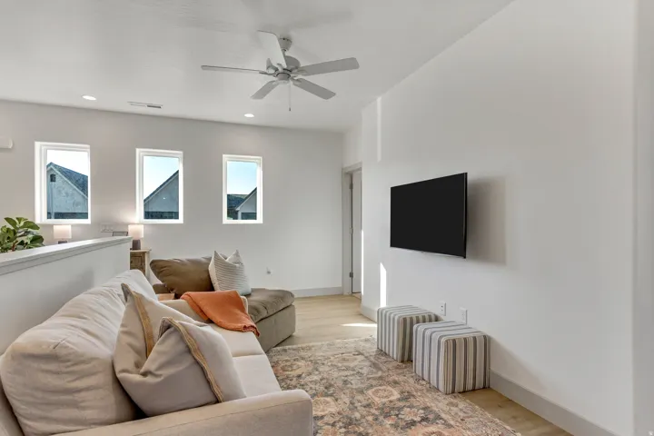 Recessed lighting, wood-finish flooring, ceiling fan, three vertical windows, open concept half wall
