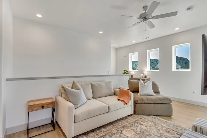Recessed lighting, ceiling fan, three windows, and light wood-finish flooring