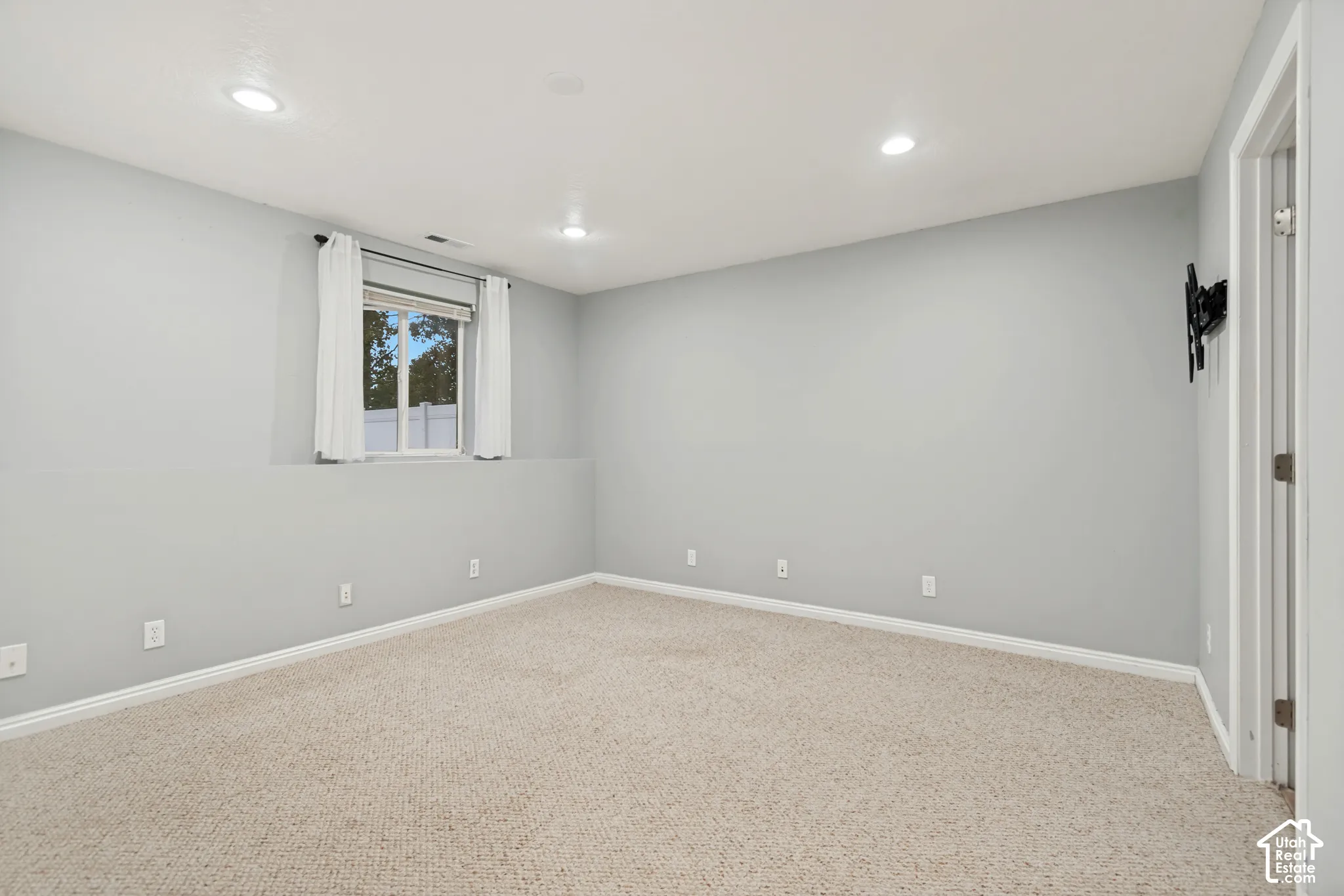 Neutral-toned interior featuring wall-to-wall carpeting, recessed ceiling lighting, and a single-pane window
