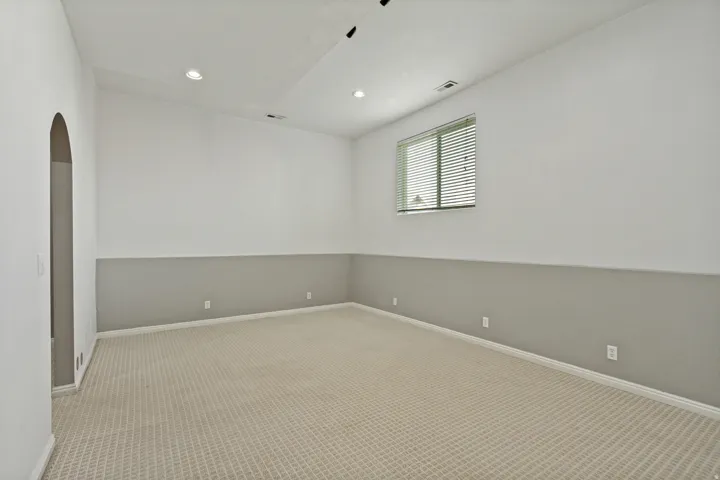 Recessed lighting, arched doorway, two-tone wall treatment, window with blinds, and patterned carpeting