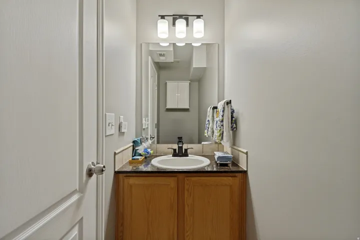 Integrated vanity with wood-finish cabinetry, dark countertop, and undermount sink