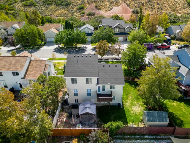 Two-story residence featuring a dark shingle roof, rear deck, and a fenced backyard with a storage shed
