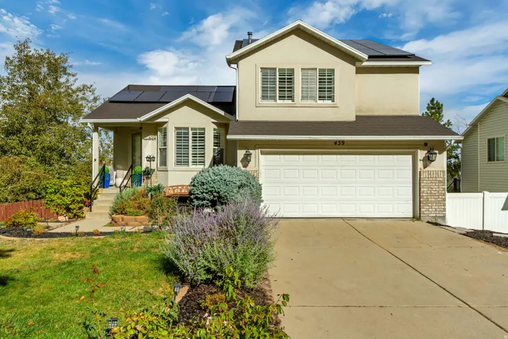 Two-story stucco residence featuring a two-car garage, solar panels, and a concrete driveway