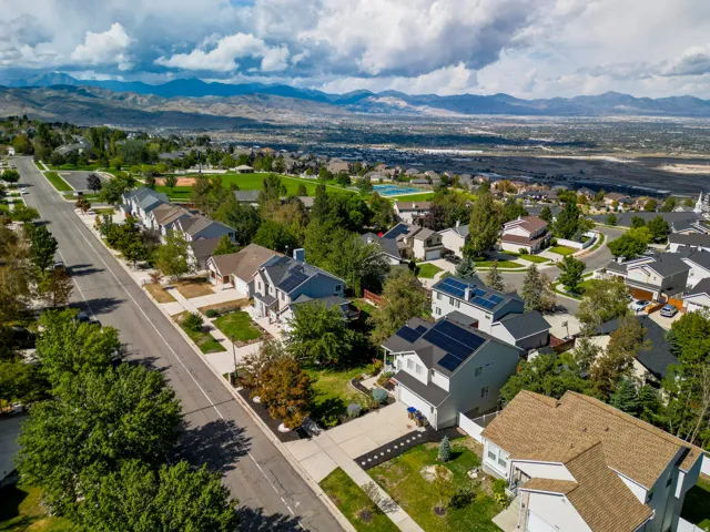 Residential neighborhood with mountain scenery, mature trees, and a community park with a pool and sports fields