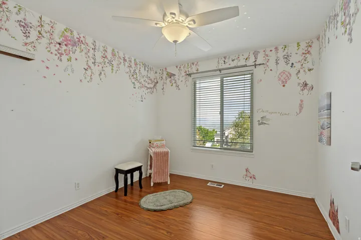Wood-finish flooring, ceiling fan with integrated lighting, window with horizontal blinds, and white painted walls