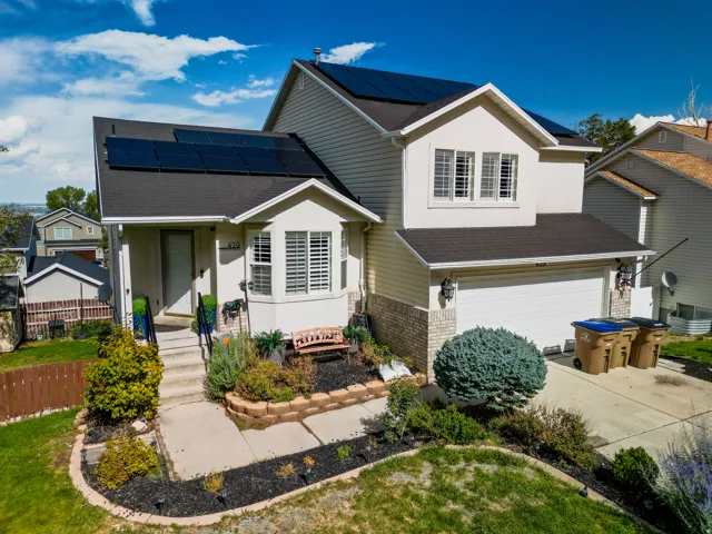 Two-story residence featuring a bay window, attached two-car garage, and solar panels