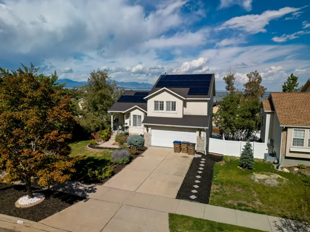 Two-story residence featuring solar panels, a two-car garage, and an extended concrete driveway