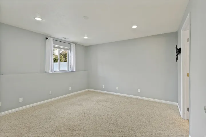 Recessed lighting, light-colored carpeting, and a window with natural light