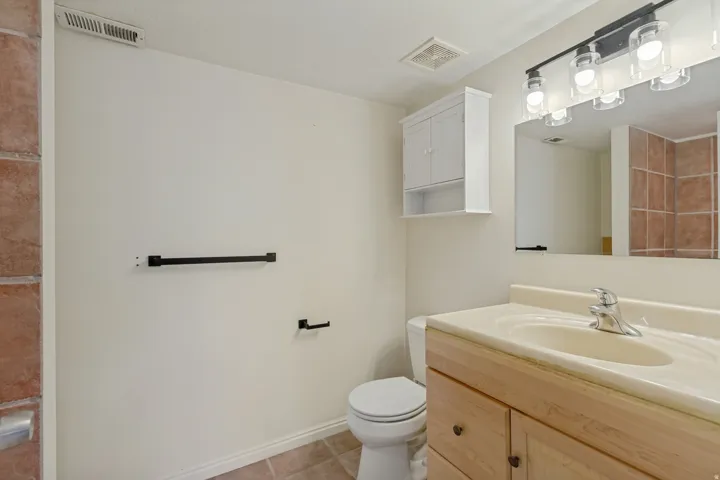 Vanity with integrated sink, wood-finish cabinetry, and wall-mounted mirror