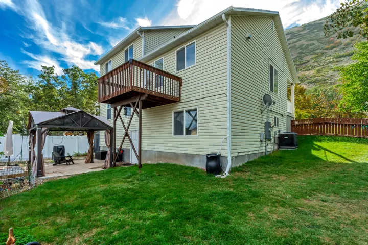 Exterior featuring a raised deck, concrete patio, and fenced yard