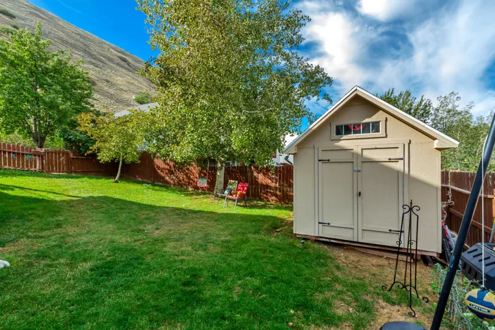Expansive green lawn, mature trees, and a private wooden fence