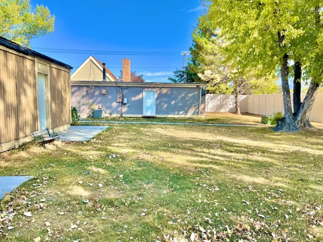 Expansive grassy yard with mature trees and a concrete patio