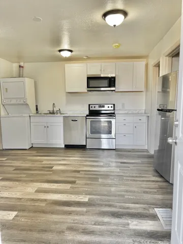 Kitchen featuring wood-finish flooring, white cabinetry, stainless steel appliances, and white countertops