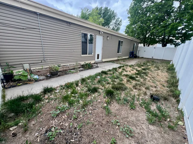Exterior featuring horizontal siding, white vinyl fencing, a concrete pathway, and a rear entry door
