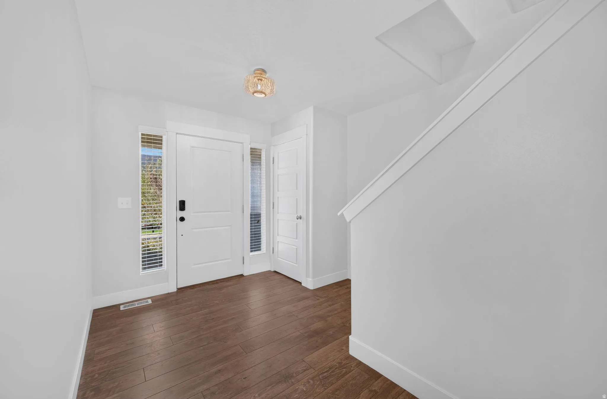 Entryway featuring wood-finish flooring, a contemporary ceiling light fixture, a paneled door, and a built-in coat closet
