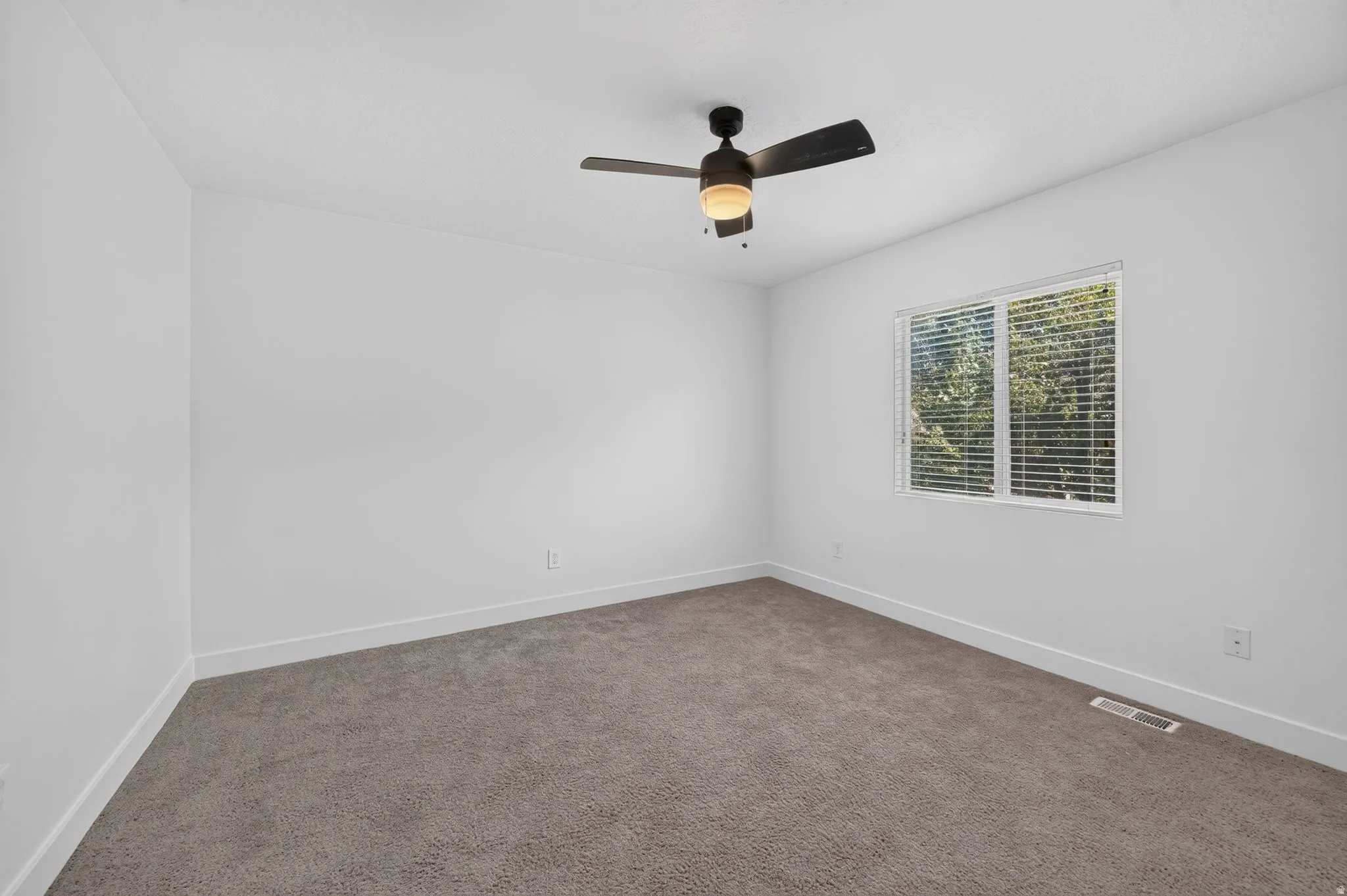 Carpeted flooring, white walls, ceiling fan with integrated lighting, and window with blinds