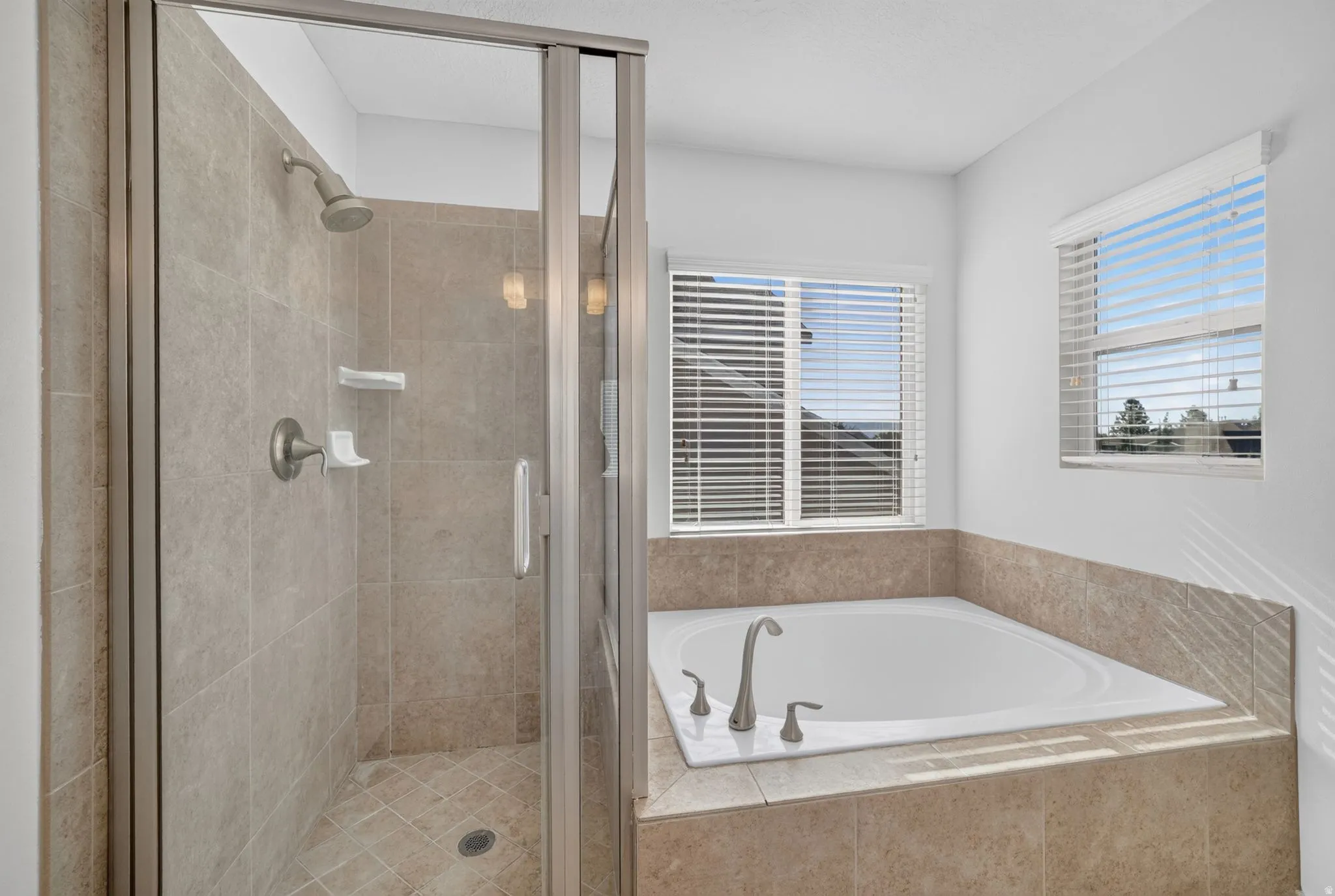 Glass-enclosed shower with tiled walls and brushed nickel fixtures