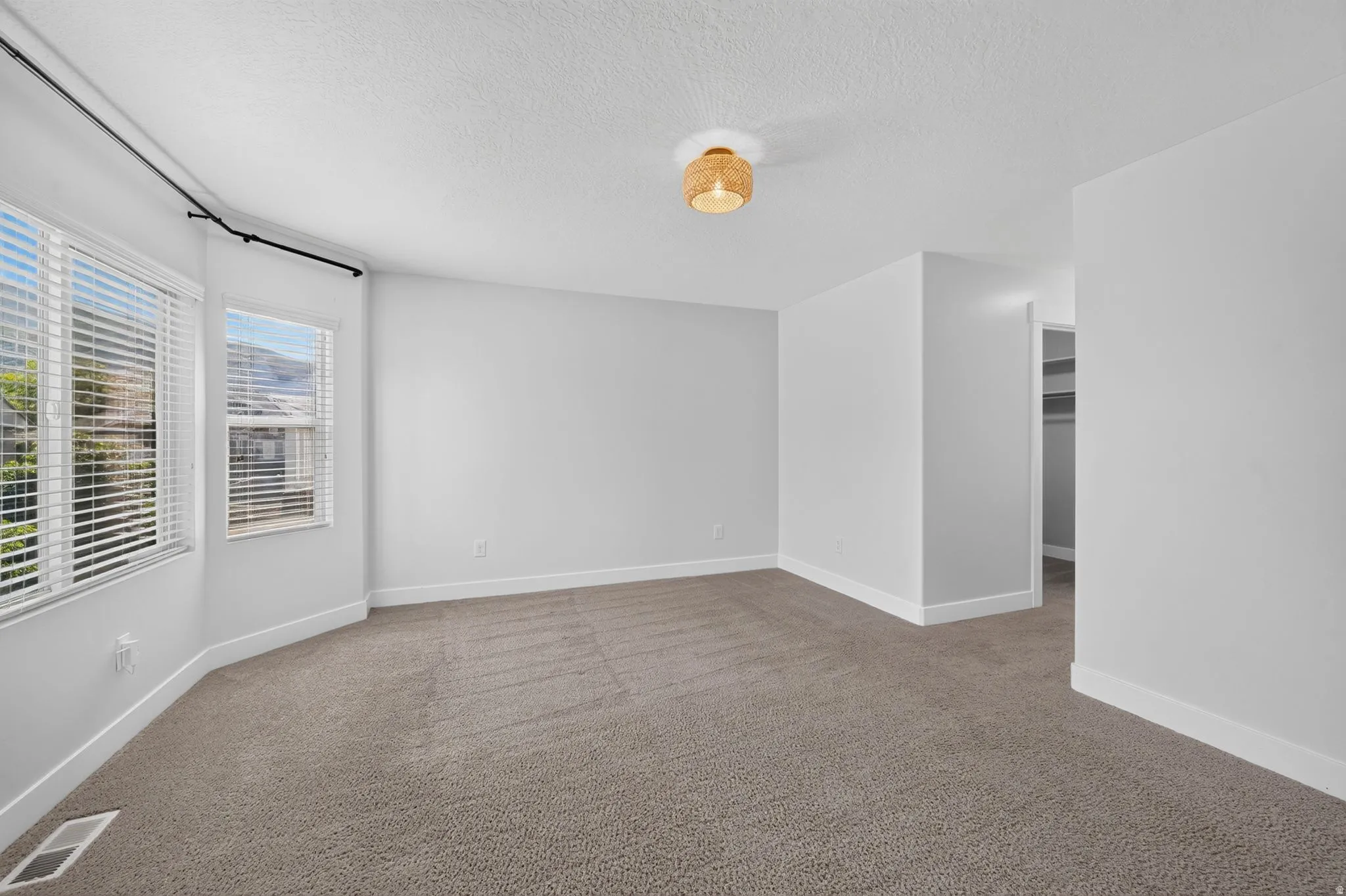 Neutral-toned carpeting with white baseboards, a built-in closet with shelving, and a decorative flush mount light fixture