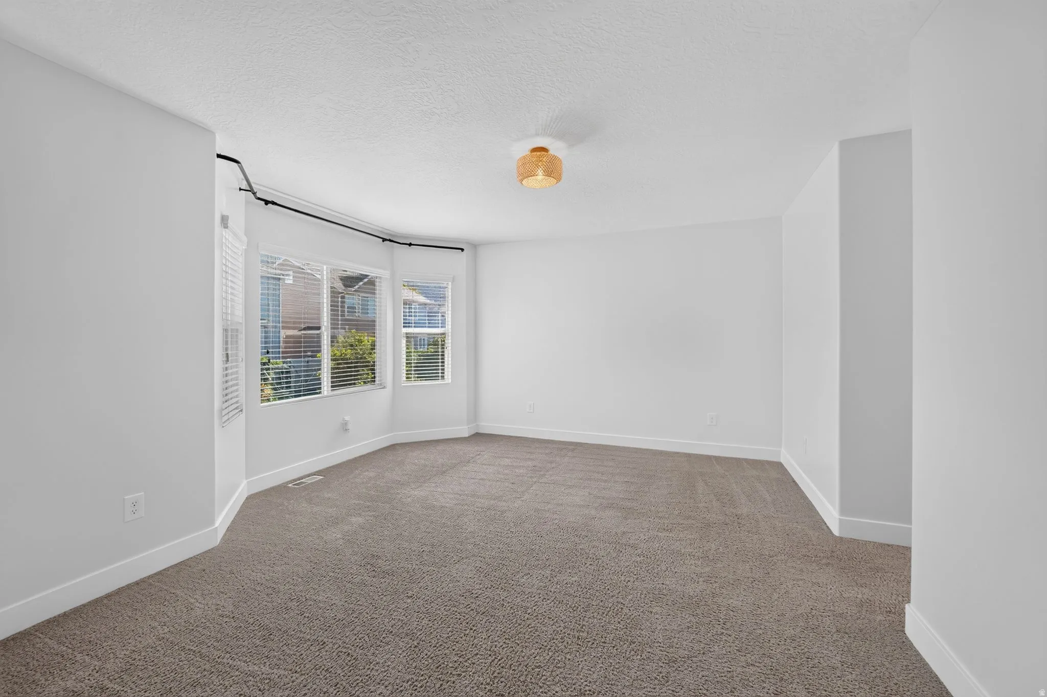Bay window with horizontal blinds, neutral carpeting, and a modern ceiling light fixture