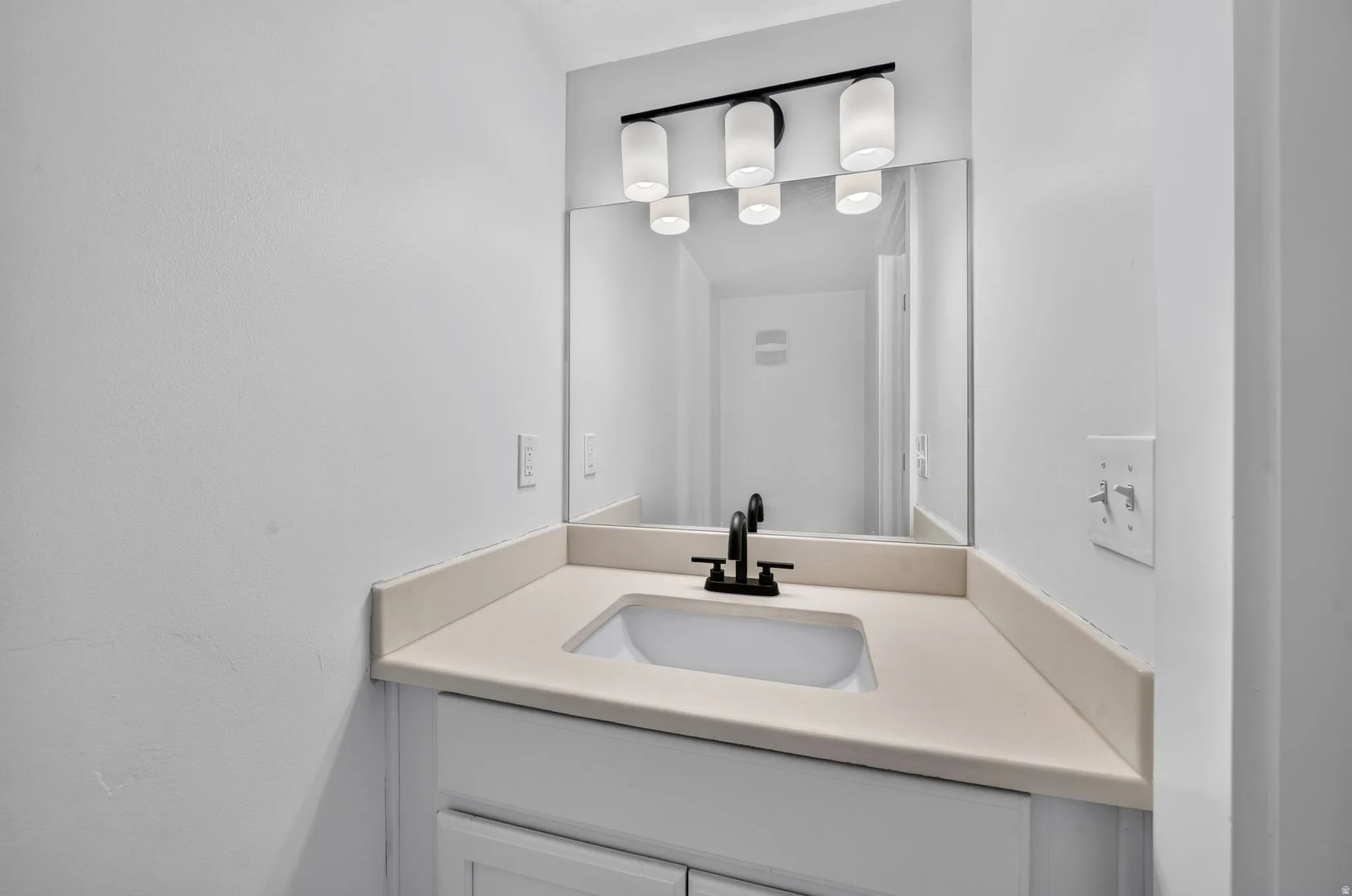 Integrated vanity with an undermount sink, a light-toned countertop, and a matte black faucet