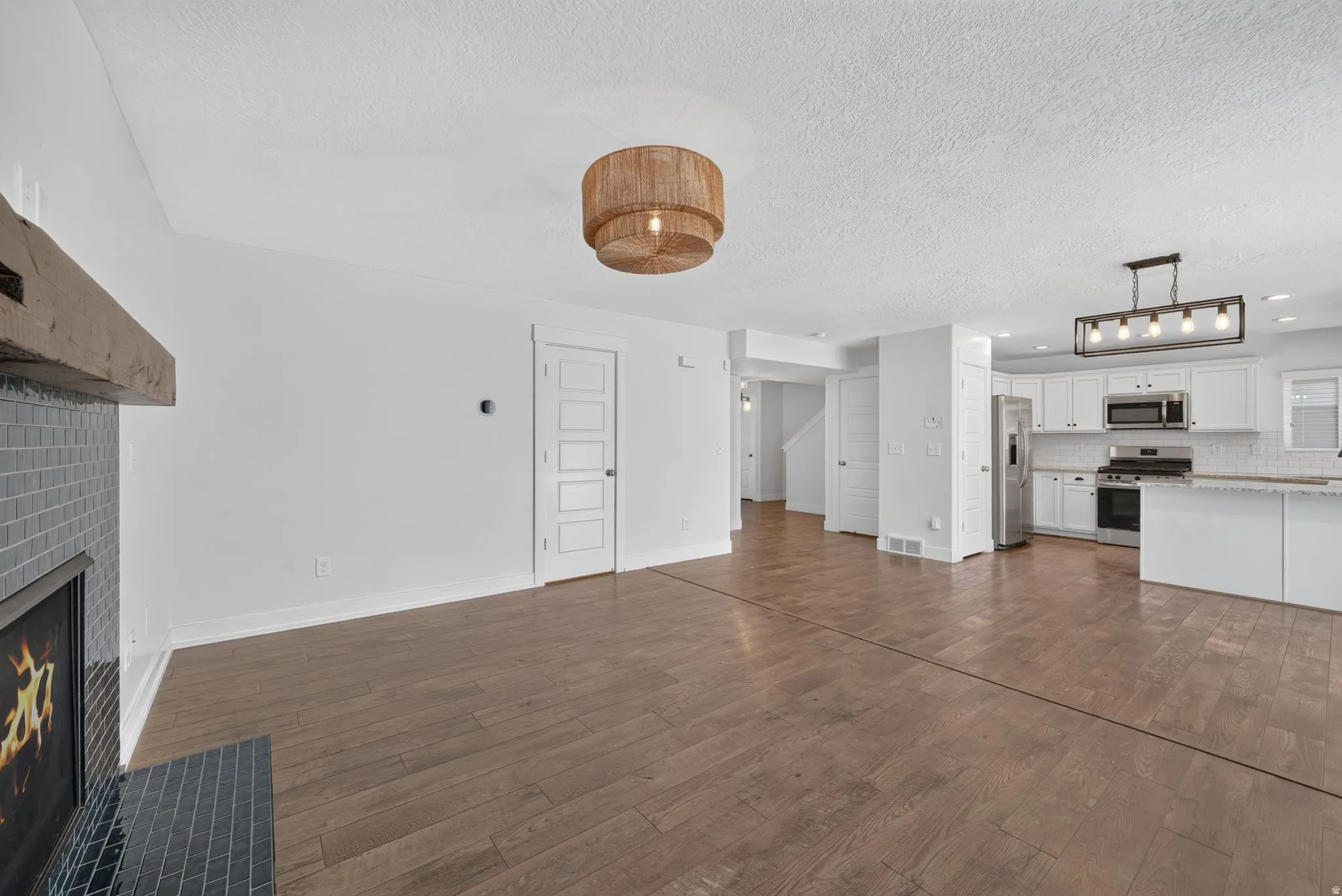 Open-concept living space featuring wood-finish flooring and a fireplace with gray tile surround