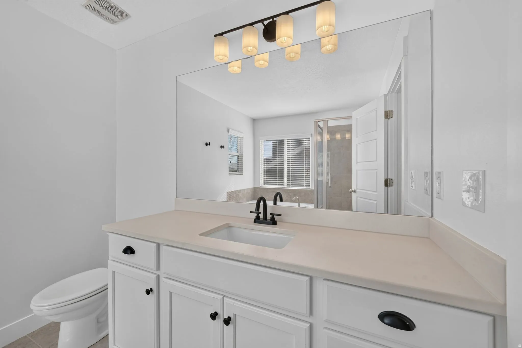 White vanity with shaker-style cabinetry, an undermount sink, and a light-toned countertop