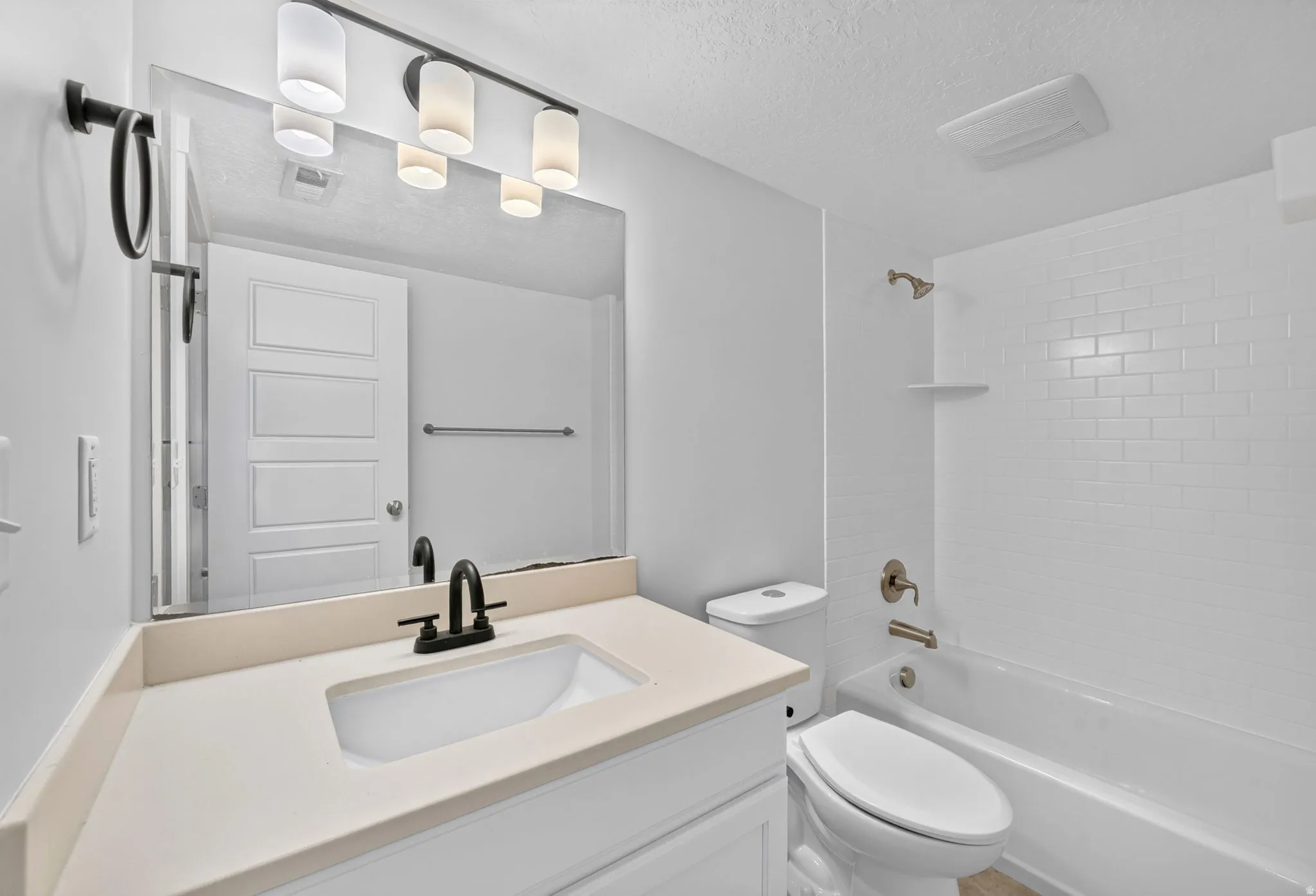 Bathroom featuring a single vanity with an integrated sink, matte black faucet, and a large mirror