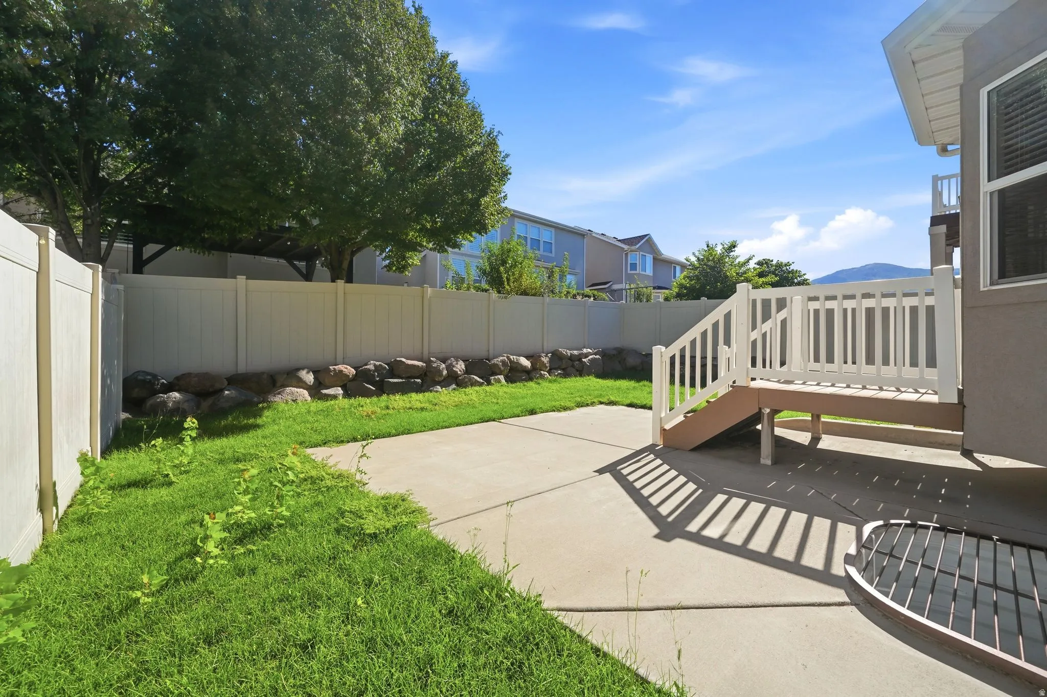 Outdoor patio featuring a privacy fence, concrete surface, and a wooden deck with white railings