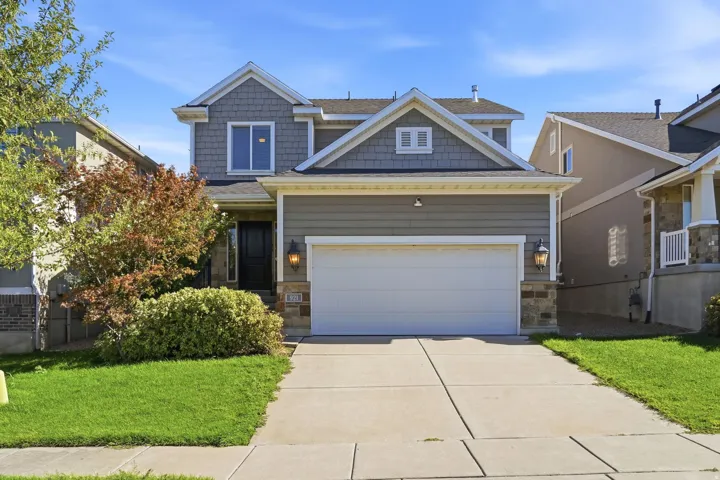 Two-story residence featuring a two-car garage, stone accents, and a concrete driveway