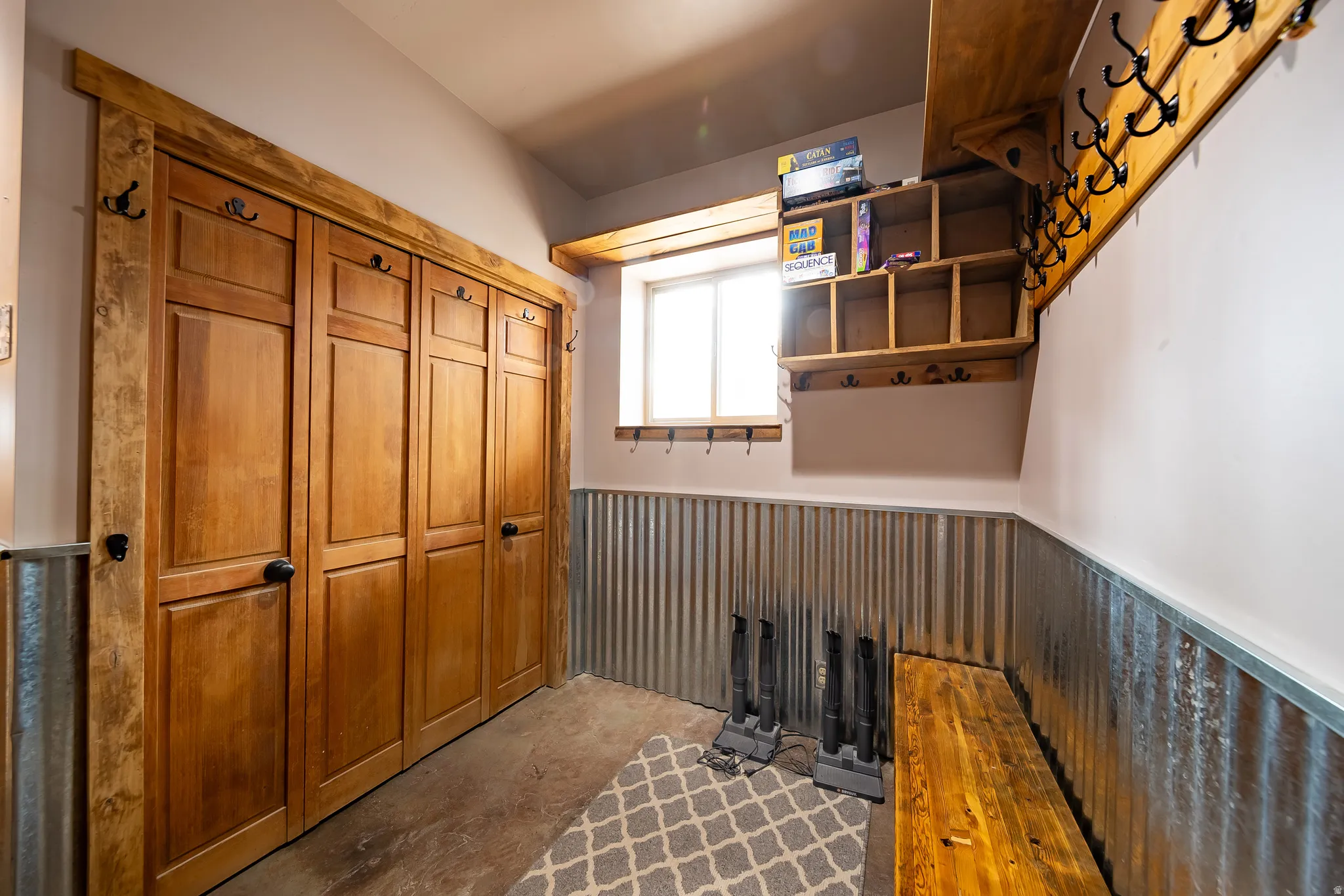 Wood-paneled bifold doors with black hardware, corrugated metal wainscoting, and a built-in wood bench