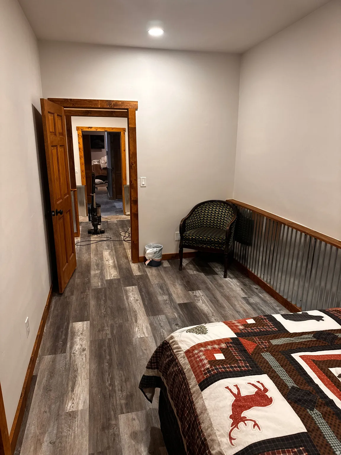 Wood-finish flooring, recessed lighting, wood-trimmed doorways, and a corrugated metal accent wall